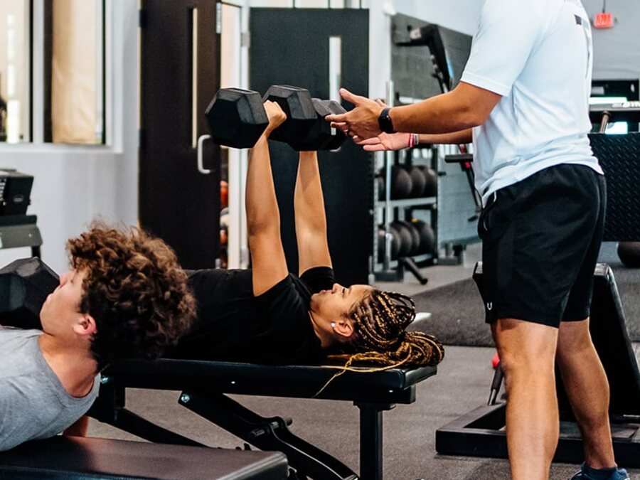A coach spotting an athlete through a pressing set